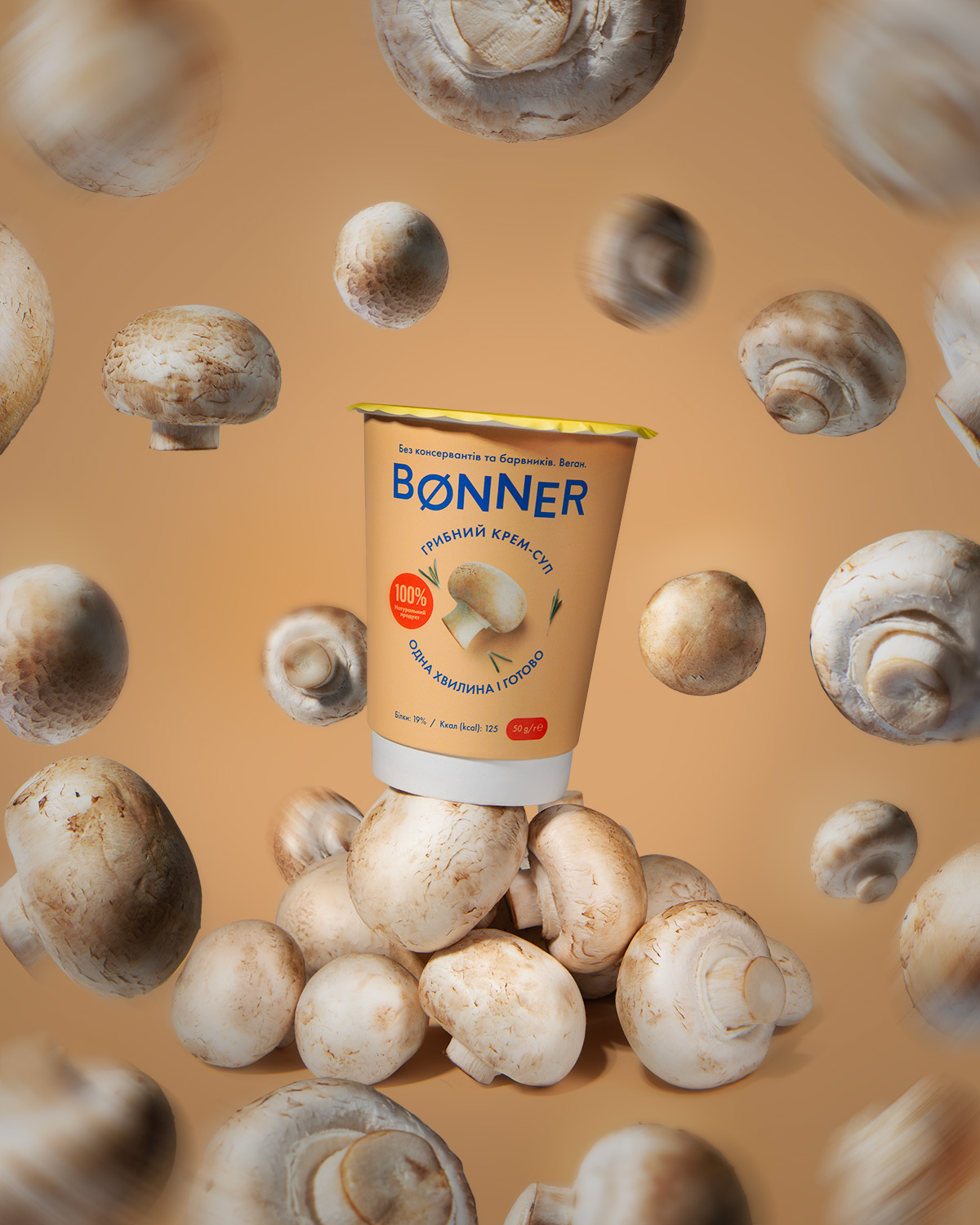 Bønner mushroom cream soup cup placed on a pile of fresh champignons, with several mushrooms floating around against an orange-brown background, creating a dynamic food advertisement.