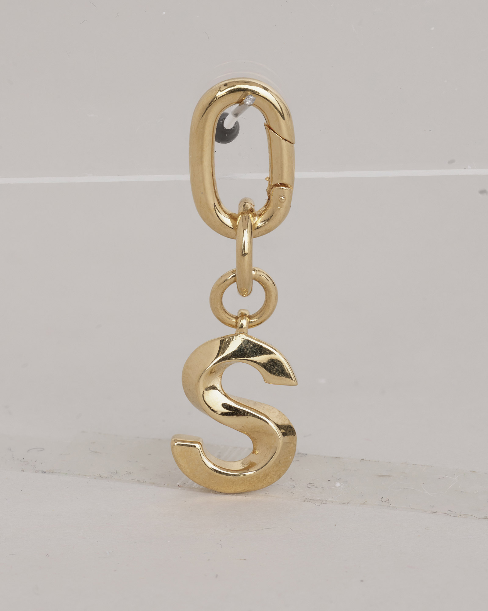 Gold 'S' initial pendant charm on a chunky chain link clasp, professional jewellery retouching for e-commerce.