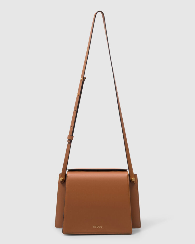 Neous minimalist tan/camel leather crossbody bag with a long adjustable strap, centered and isolated on a clean white background for e-commerce.