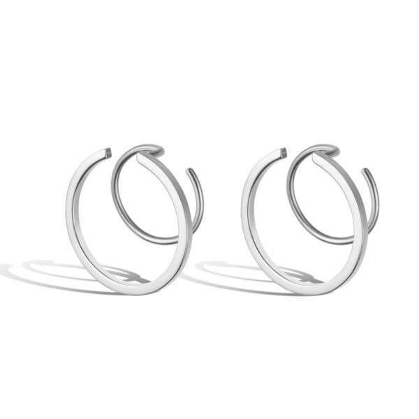 Pair of modern silver or white gold double-hoop or interlocking C-shaped earrings, photographed for e-commerce with sharp highlights and defined shadow.